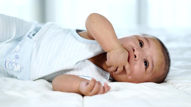 little baby with finger in mouth on a bed