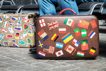 suitcase with stickers from around the world stands on the platform in the waiting room. Tourist or passenger waiting for train or plane