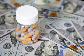 Pills in a bottle on US dollars bills. Concept of health care, medication in capsules, pharmaceutical business, drug prices, pharmacy, medicine and economics