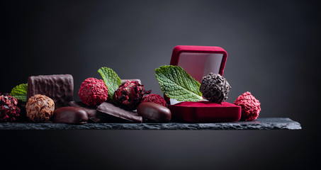 Various chocolates with mint leaves on a black background.
