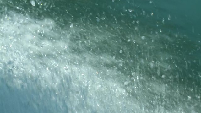 Extreme close-up high-angle moving shot of foamy water splash from a speeding tour motorboat, Temenggor Lake, Kuala Lumpur, Malaysia