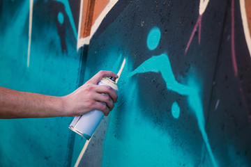 Street artist painting colorful graffiti on generic wall - Modern art concept with urban guy performing and preparing live murales with multi color aerosol spray © Graphicroyalty