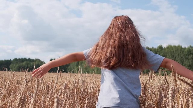 A girl with red hair runs across the field. Slow motion.