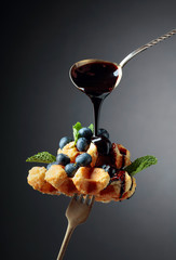 Homemade Belgian waffles with  chocolate syrup, blueberry and mint.