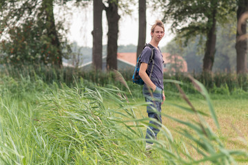 Naklejka na ściany i meble Young man with backpack enjoys the countryside.