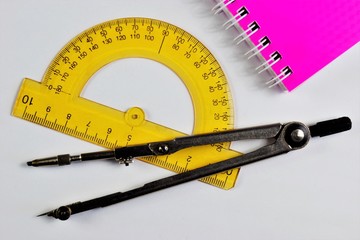 A tool for drawing lesson at school. Drawing — a graphic image made on a scale, protractor for drawing angles, a compass for drawing circles, a book for solving the tasks.