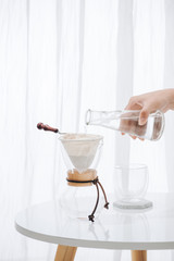 Fototapeta na wymiar Pouring Water to the Coffee Pot on White Wall and White Table, Manual Brew, Hand Drip Coffee