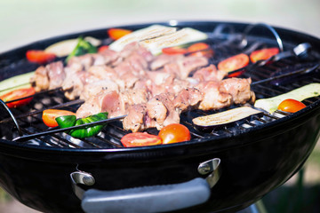 pieces of barbecue pork meat on a skewer with vegetables on the grill