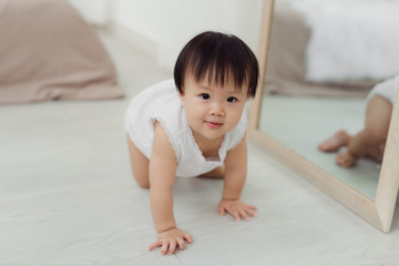 Adorable little baby girl crawling on floor in room