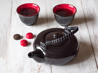 two red cups tea and black teapot on the  white wooden table, top view