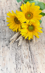 bouquet of sunflowers with dry wheat on a rustic table