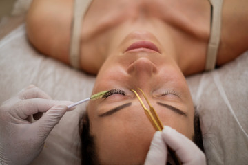 Obraz na płótnie Canvas Procedure of eyelash extension in salon by cosmetician