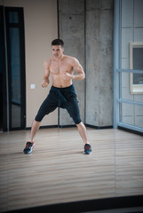Naklejka premium An athletic man boxer in black shorts training in the bright studio