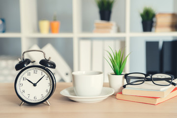 Classic vintage  alarm clock and  coffee cup on wooden background