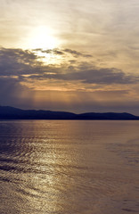 Greece, the Aegean sea. A view from a ferry sailing at sunset. The sunset over the distant isle of Kythnos. An atmospheric sky. Natural beauty. Nature, open air and calmness.