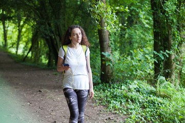 Young woman listening to music while walking in forest