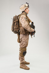 Soldier in US marines uniform with rifle on light grey background, studio shot