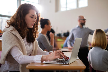 Beautiful girl taking notes in multinational group of students in an auditorium
