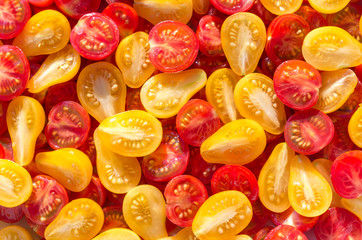 Fototapeta na wymiar Fresh halves of Mexican cherry tomatoes. Sliced yellow and red cherry tomatoes.Background of many colorful cherry tomatoes. Cherry tomatoes top view.