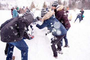 group of young people making a snowman