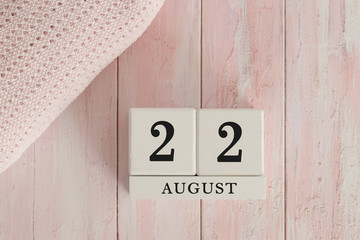 22 August Date on Cubes. Date on painted pink wood, next to baby blanket. Theme of baby due dates and birth dates.