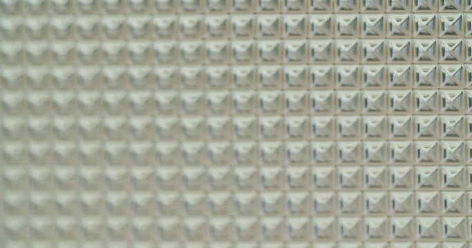 a pattern of many geometric squares on a plexi glass plate, is moving from top to bottom.