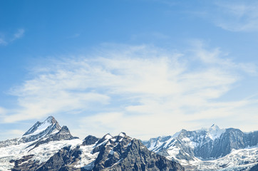 Alpine mountain peaks with blue sky and light clouds. Mountain climbing. Copy space, place for text. Motivational background. Reaching goals. Personal development. Challenge concept