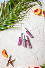 Wonderful beach. Lipstick, lip gloss, lip balm lie on the sand, surrounded by juicy fruits,...