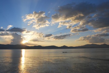Sky at sunset and a boat in the middle of the sea.