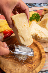 Man cooking with hard italian cheese, grated parmesan or grana padano cheese, hand with grater