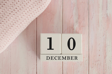 10 December Date on Cubes. Date on painted pink wood, next to baby blanket. Theme of baby due dates and birth dates.
