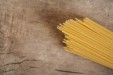 Yellow long spaghetti on an old wooden background. Food concept background. Top view. Copy, empty space for text