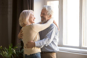 Happy old retired romantic couple dancing laughing in living room