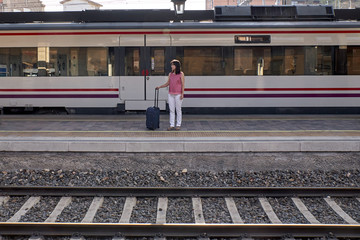 woman waiting for the train with a suitcase