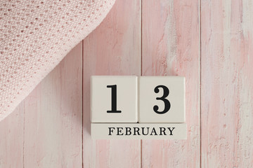 13 February Date on Cubes. Date on painted pink wood, next to baby blanket. Theme of baby due dates and birth dates.