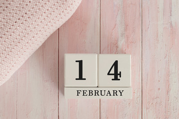 14 February Date on Cubes. Date on painted pink wood, next to baby blanket. Theme of baby due dates and birth dates.