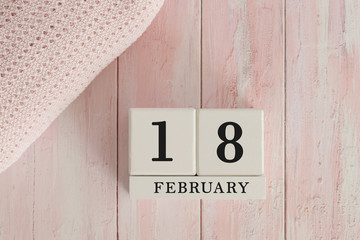 18 February Date on Cubes. Date on painted pink wood, next to baby blanket. Theme of baby due dates and birth dates.