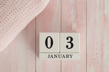 3 January Date on Cubes. Date on painted pink wood, next to baby blanket. Theme of baby due dates and birth dates.