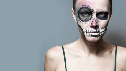 Halloween. Beautiful woman with bright black halloween makeup isolated over gray background
