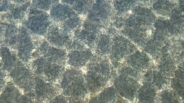 Reflexionen der leicht bew&ouml;lkten Sonne im Wasser eines seichten Springbrunnens