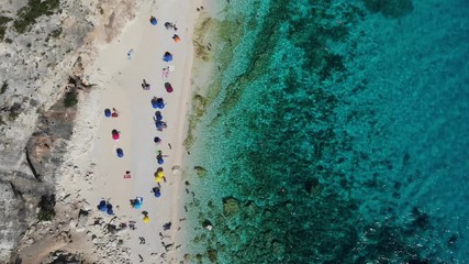 View from above, stunning aerial view of a beautiful beach full of beach umbrellas and people sunbathing and swimming on a turquoise water. Cala Gonone, Sardinia, Italy, Cala Mariolu