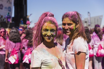 Obraz premium Smiling portrait of a young women with holi powder on their face looking at camera