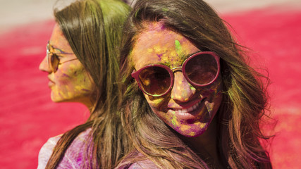 Close-up of two women wearing sunglasses covered with holi color powder