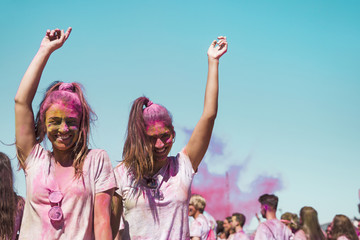 Two young women covered with holi color dancing in the holi festival