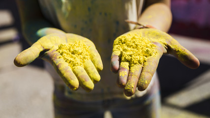 Close-up of woman's hand showing yellow holi color