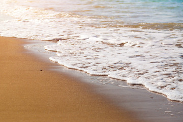 The sandy beach is yellow in color and the waves are rolling in ocean Sea waves wash sand.