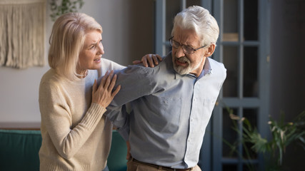 Worried mature wife supporting senior husband feel sudden back pain