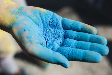 Close-up of a person's hand holding blue holi color