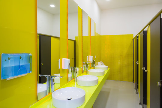 Public toilet with yellow walls. Toilet with cubicles with bright yellow walls. Modern toilet design.