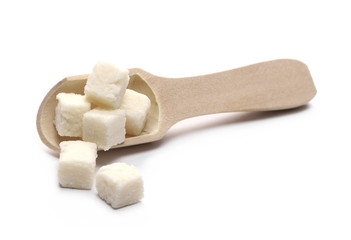 Coconut cubes, pieces, healthy sliced and diced snacks with wooden spoon isolated on white background